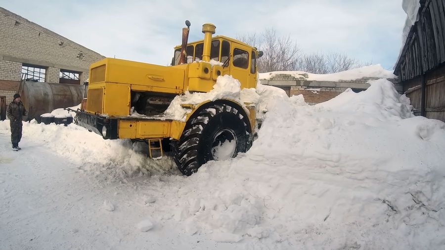Старый трактор К-700 «Кировец» выбирается на дорогу из огромного сугроба