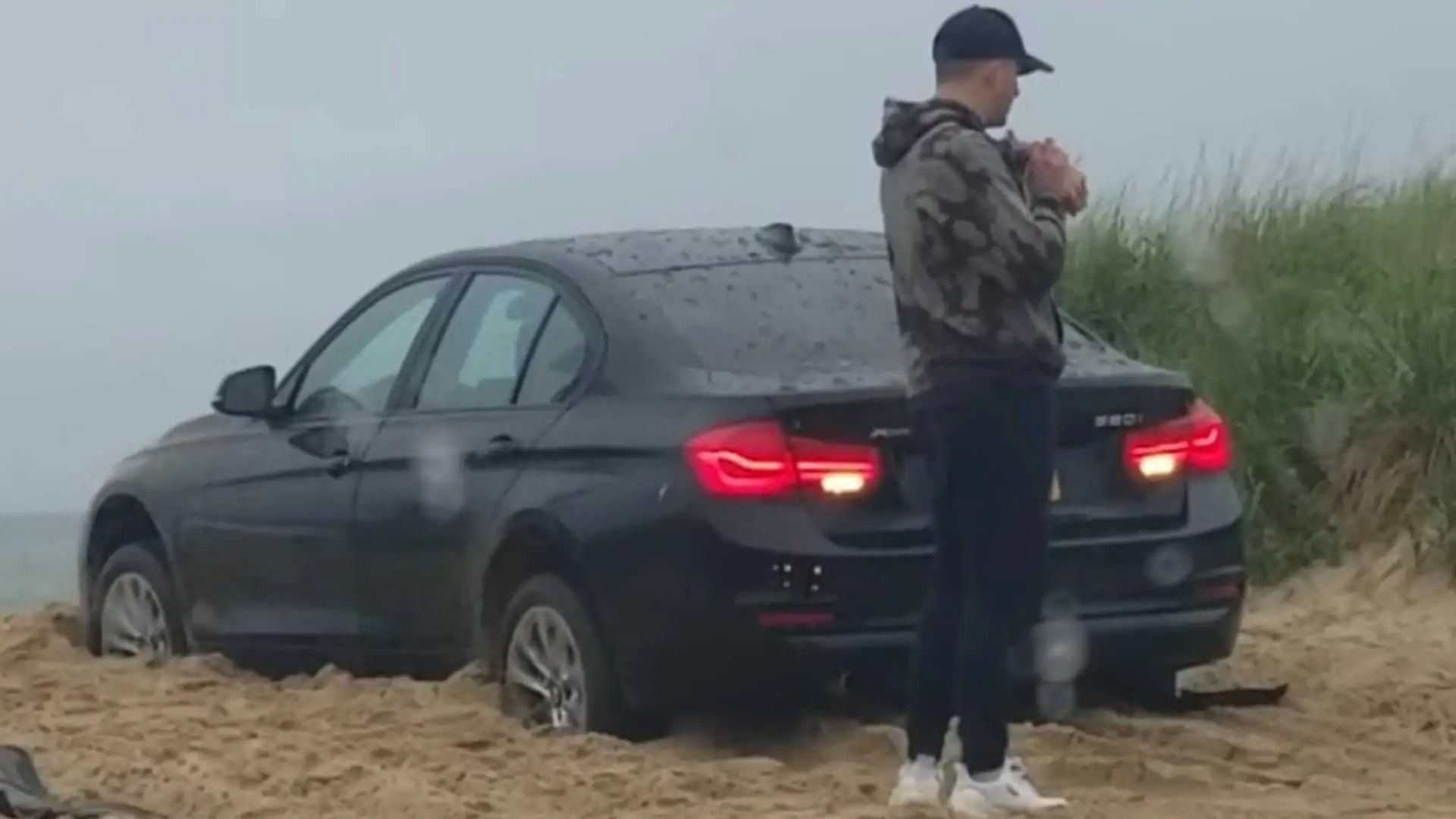 Посмотрите, как застрявший BMW самостоятельно пытается выбраться из песка, пока его владелец стоит снаружи